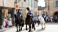 L'arrivée de d'Artagnan dans Lupiac sur son cheval, suivi des mousquetaires, avec des personnes en costume d'époque et des visiteurs